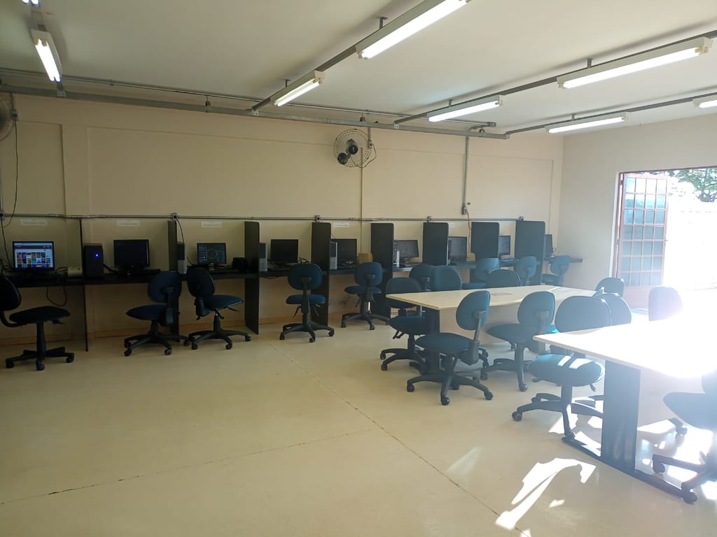 Sala de informática em ambiente acadêmico, com computadores alinhados em laboratório de TI