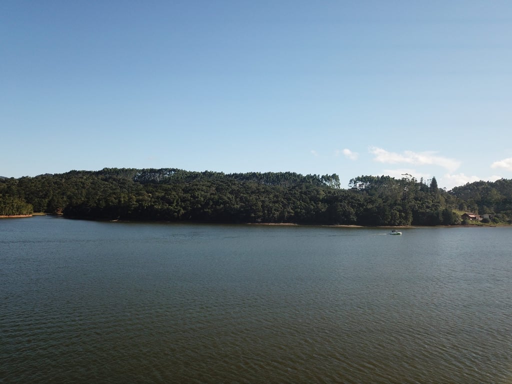 Paisagem de lago em Rio dos Cedros, cercado por morros e vegetação atlântica