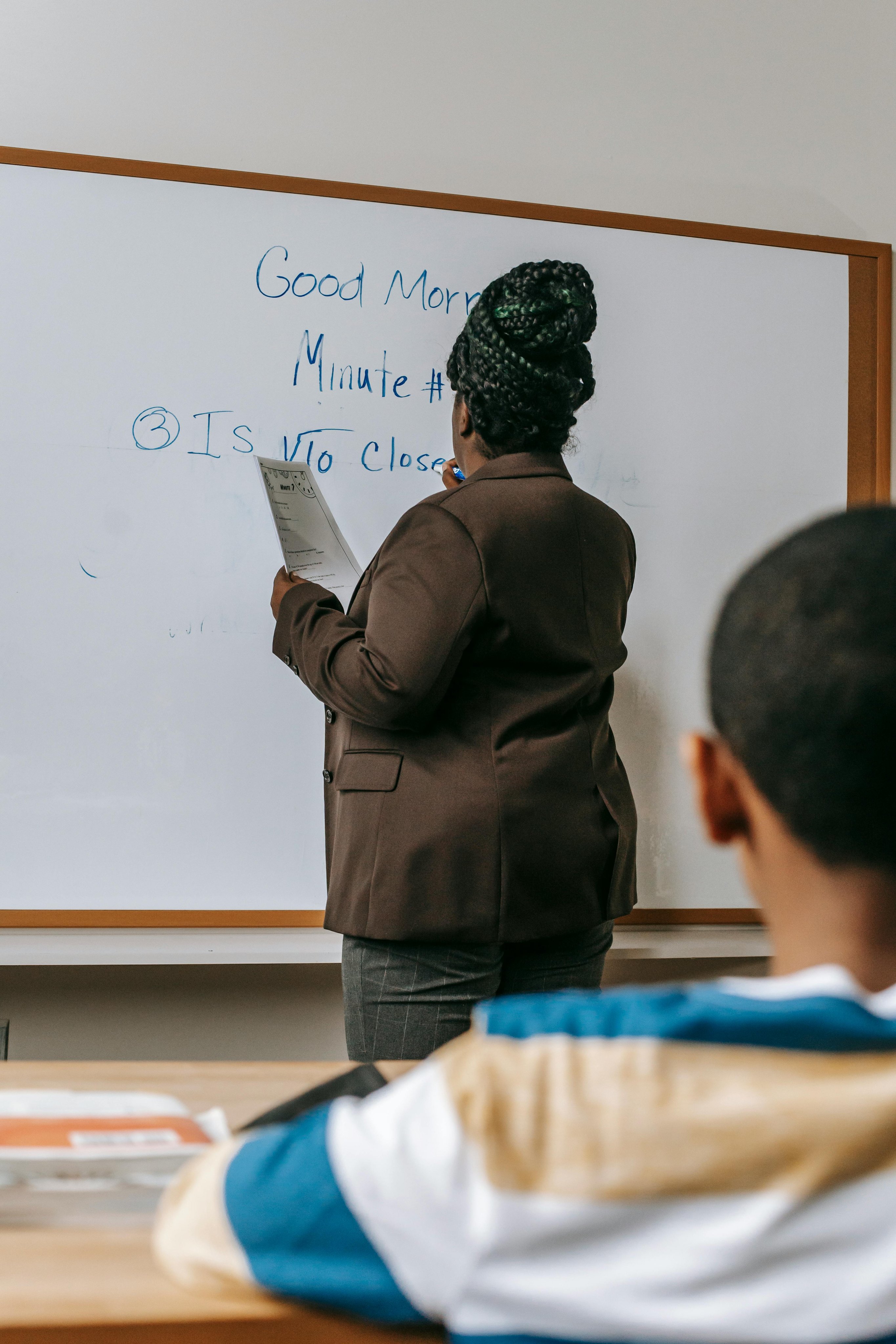 Professora em quadro branco e turma atenta em sala de aula pública
