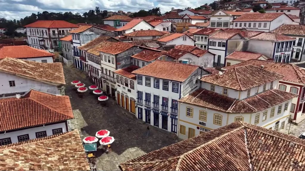 Paisagem urbana de cidade pequena no interior do Rio Grande do Sul, ao entardecer, com casas baixas e ruas arborizadas