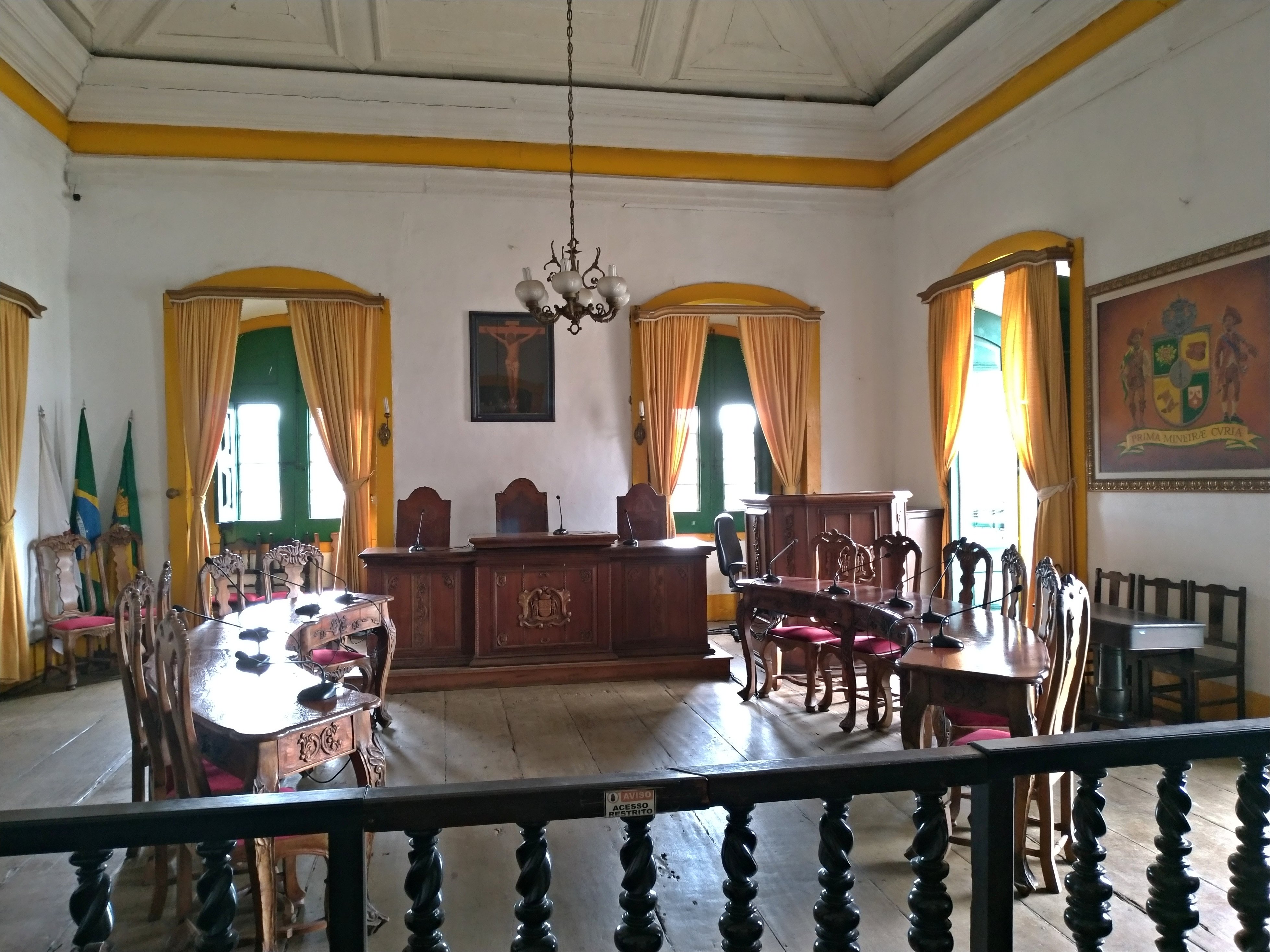 Interior de uma câmara municipal no Brasil, com mesas e cadeiras para vereadores