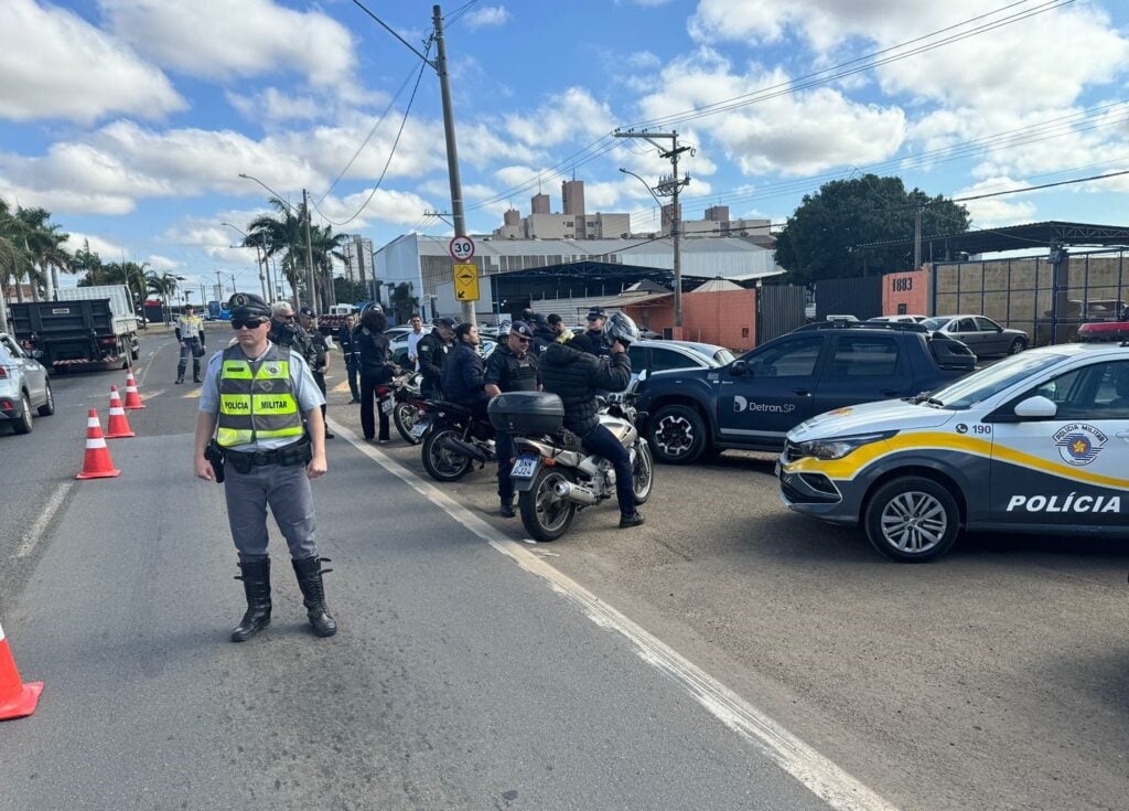 Agentes de trânsito em operação de fiscalização com coletes refletivos e cones em via urbana