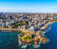 Vista aérea da orla de Salvador com o Farol da Barra ao entardecer