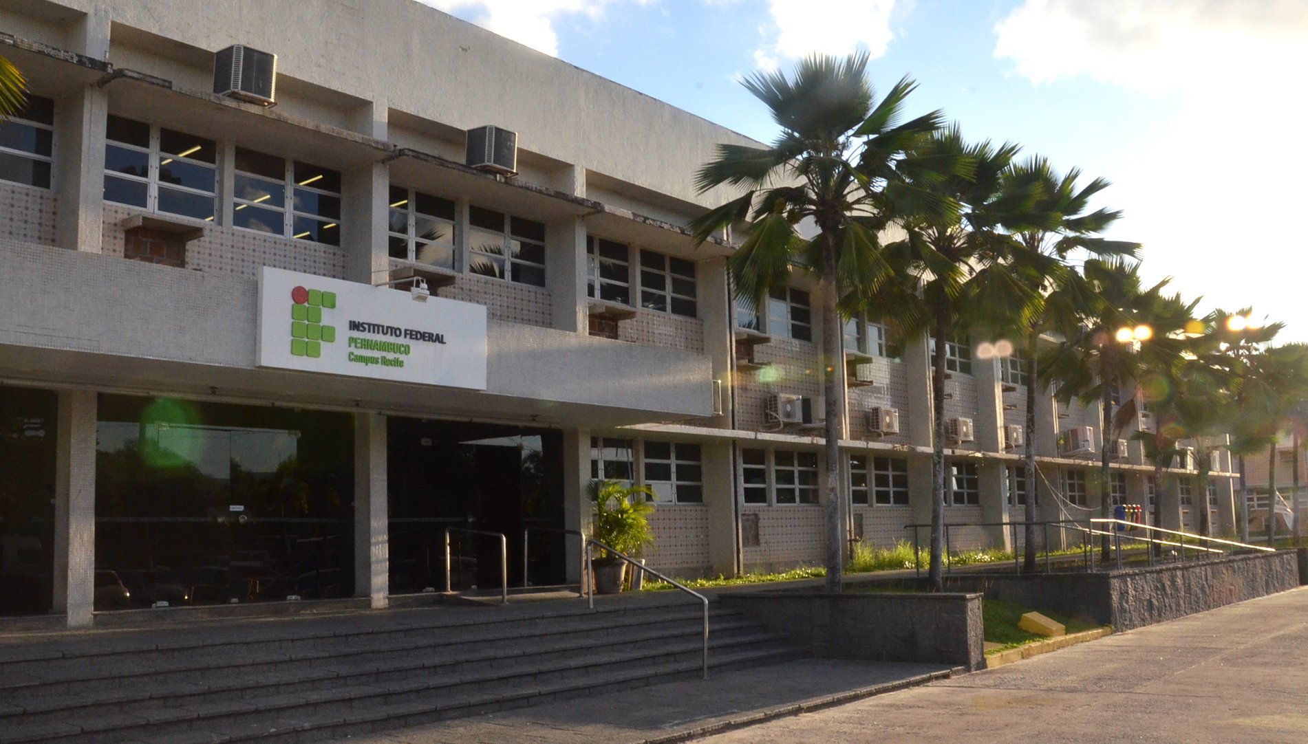 Fachada de um Instituto Federal, com prédio e palmeiras, ilustrando ambiente acadêmico público federal