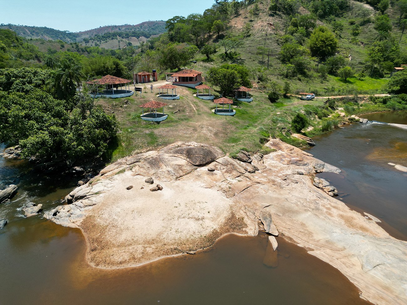 Paisagem de região serrana de Minas Gerais, com rio e vegetação, sugerindo interior mineiro