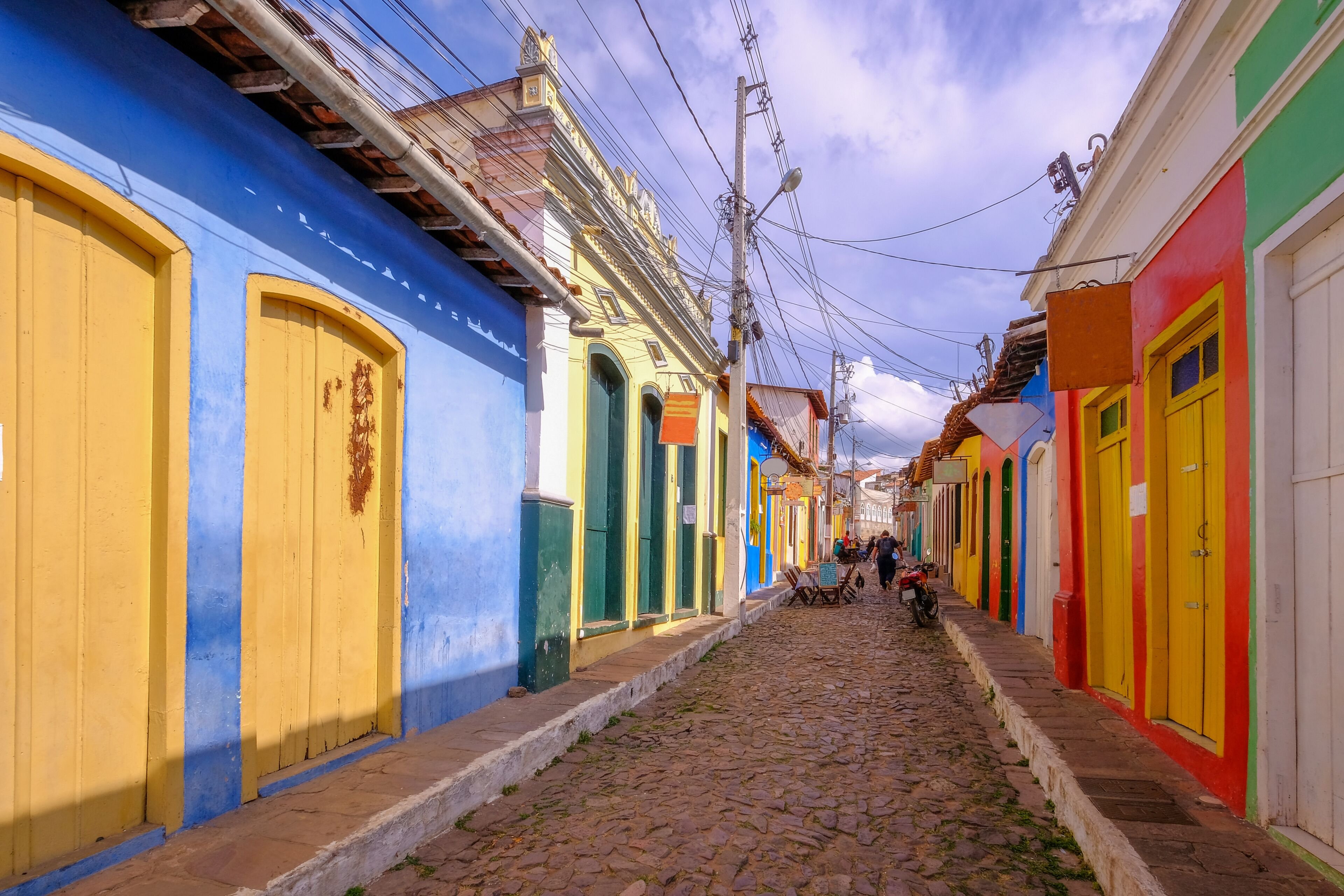 Rua de cidade do interior da Bahia sob céu azul, com casas coloridas e calçamento de pedras