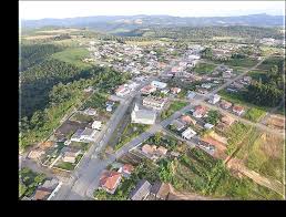 Vista aérea de pequena cidade do Oeste catarinense, com núcleo urbano e áreas rurais ao entardecer