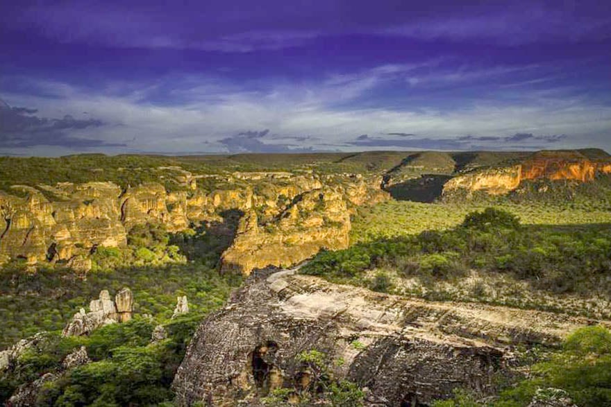 Paisagem do semiárido piauiense ao entardecer, com céu amplo e formações rochosas em primeiro plano