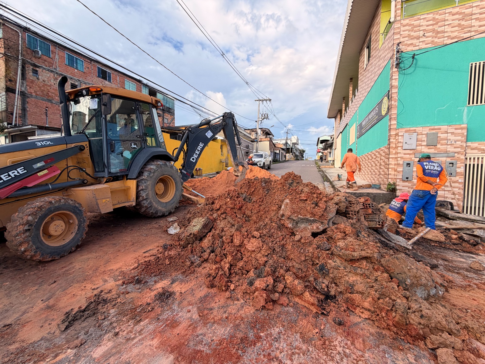 Equipe de manutenção urbana em atividade, com maquinário e trabalhadores em via pública