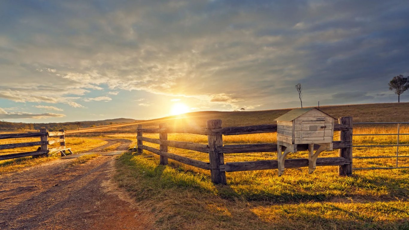 Paisagem rural no Oeste catarinense ao entardecer, com lavouras e cercado de madeira