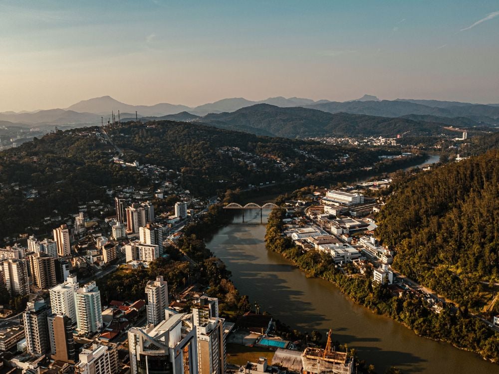 Vista aérea de Joinville SC com morros ao fundo e áreas urbanas em destaque
