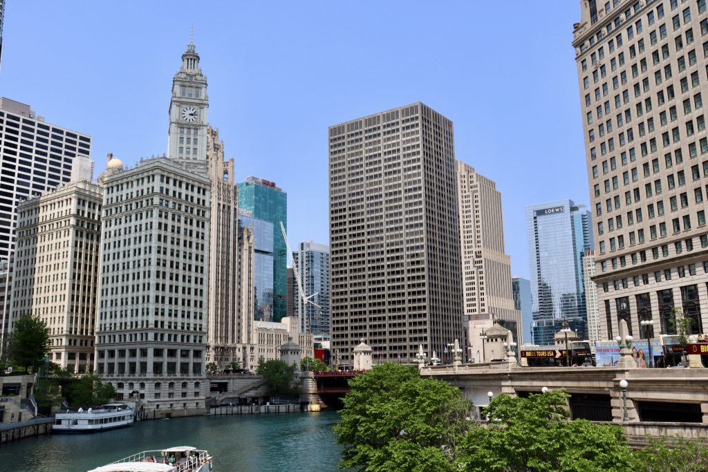 Cenário urbano contemporâneo, com edificações e área verde às margens de um curso d'água, em foto horizontal de estilo editorial