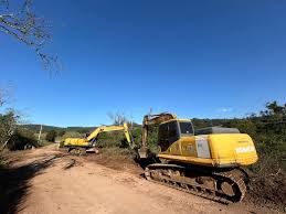 Retroescavadeira em manutenção de estrada rural