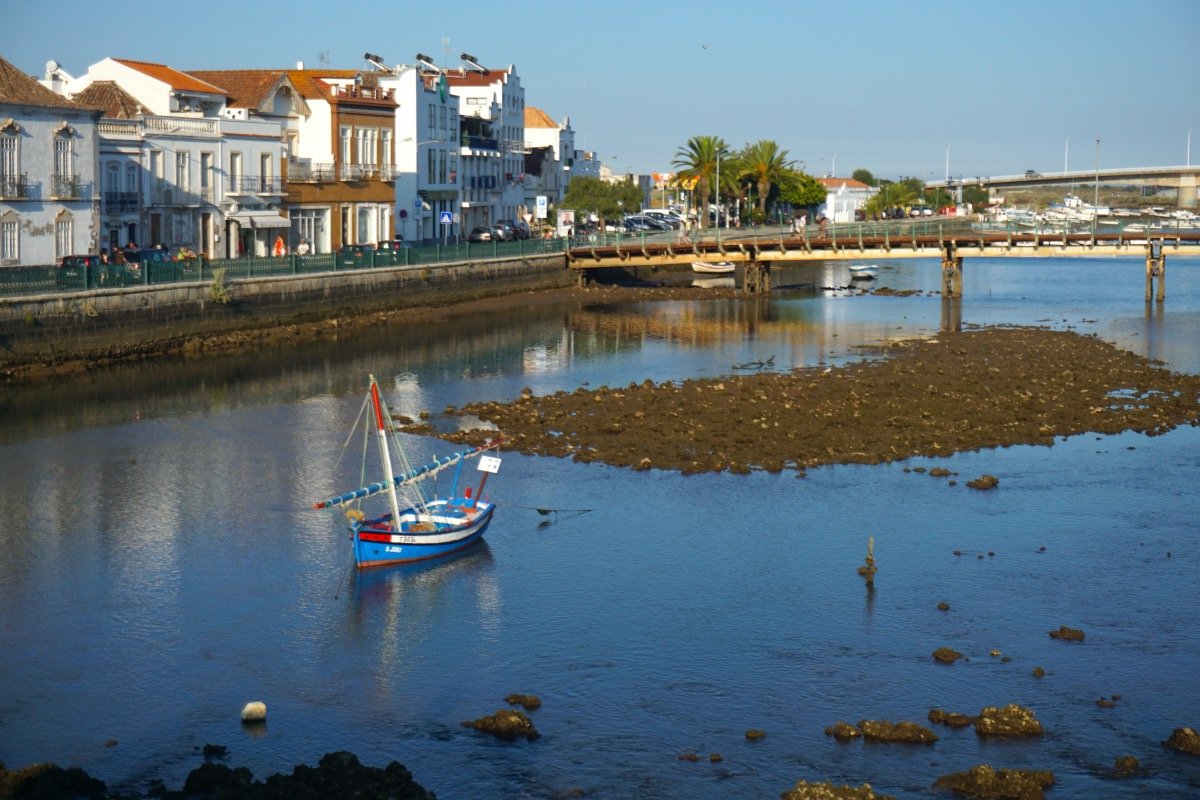 Cena ribeirinha urbana na Amazônia, com casas coloridas à beira d’água e embarcação