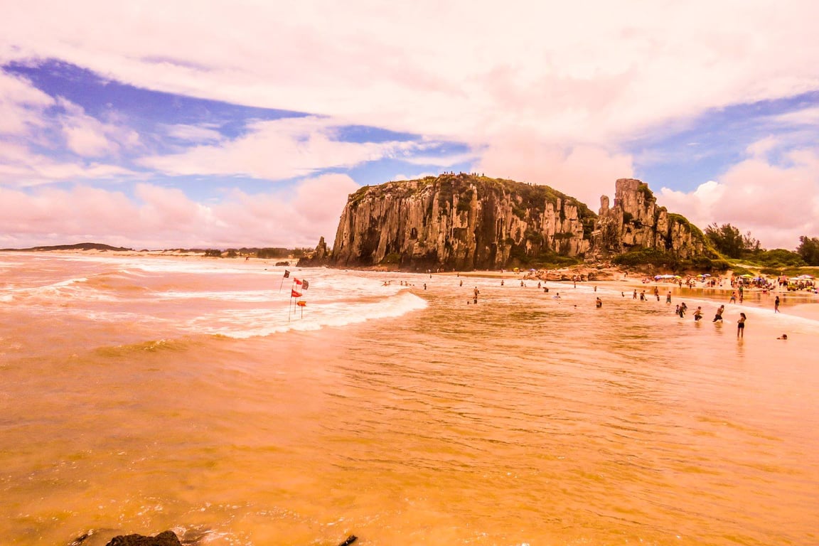 Vista aérea de Torres RS ao pôr do sol, com falésias e orla