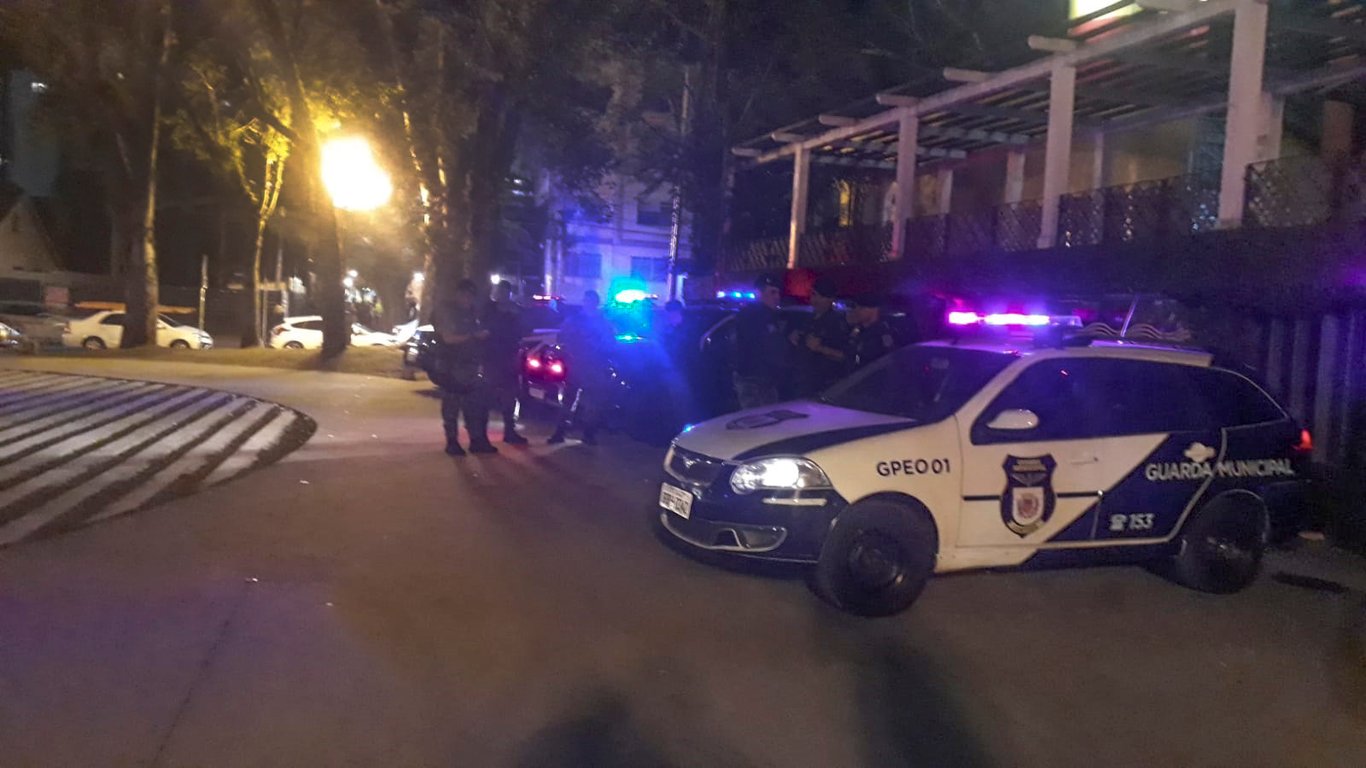 Viatura de guarda municipal com luzes ligadas em cena urbana noturna