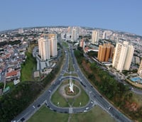 Vista aérea de cidade do interior paulista, com área urbana e vegetação ao redor, em dia claro