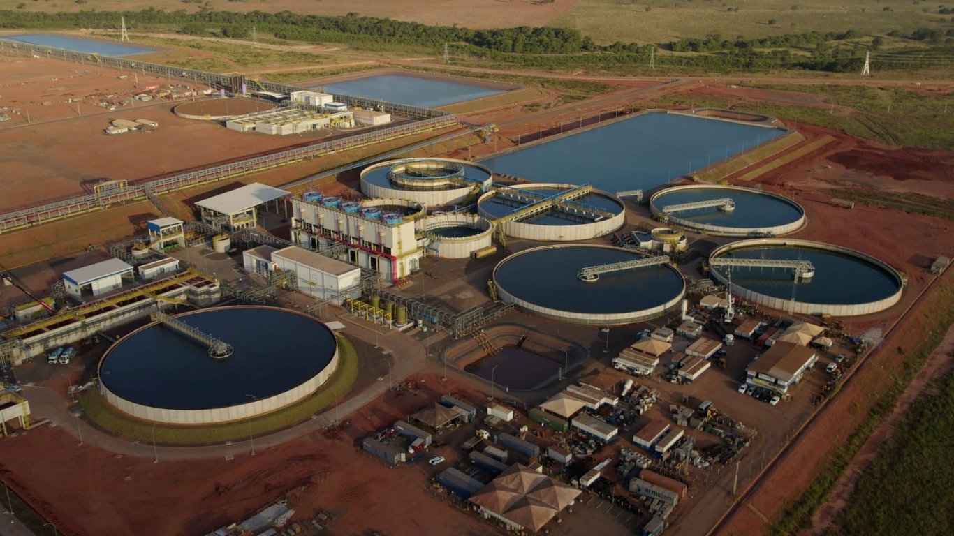Infraestrutura de estação de tratamento de água ao pôr do sol, com tanques de clarificação e filtração vistos de cima