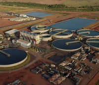 Infraestrutura de estação de tratamento de água com tanques de clarificação e filtração ao pôr do sol, vista de cima.