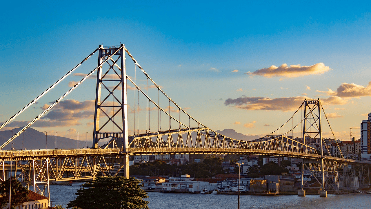 Ponte Hercílio Luz ao pôr do sol, com vista aérea da baía de Florianópolis