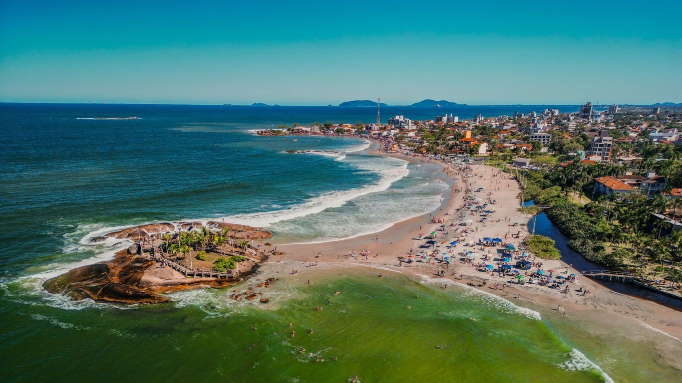 Vista aérea de Itapoá, litoral norte de Santa Catarina, com faixa de areia e área urbana sob céu azul