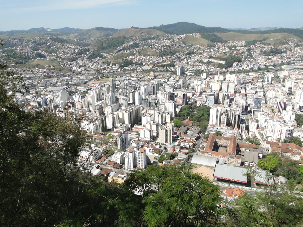 Vista panorâmica de Juiz de Fora ao entardecer, com prédios e áreas verdes