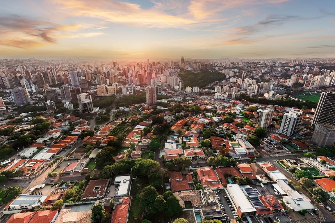 Vista aérea de Campinas SP ao entardecer, com skyline urbano e tons quentes de fim de tarde