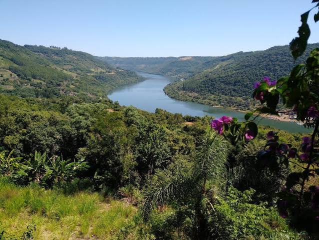 Paisagem do rio Uruguai com margem arborizada e céu aberto, na região Noroeste do Rio Grande do Sul