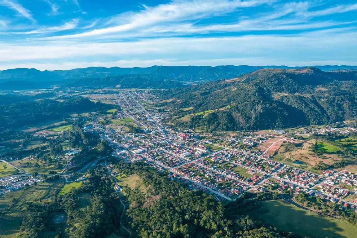 Paisagem urbana no interior de Santa Catarina, com morros ao fundo e céu aberto