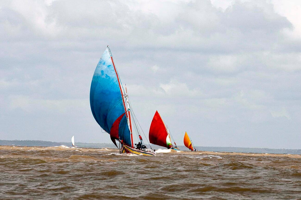 Comunidade pesqueira tradicional com jangadas coloridas em águas rasas, extremo sul da Bahia