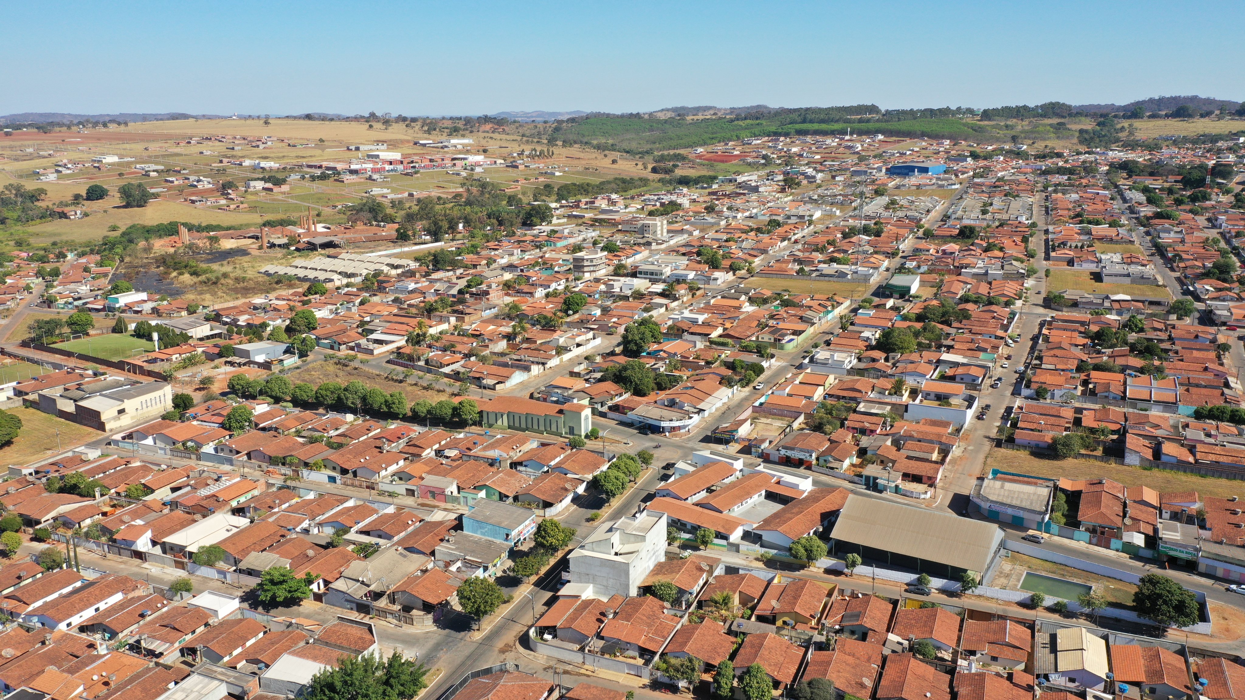 Vista aérea de Inhumas GO ao entardecer, com áreas residenciais e vegetação ao fundo