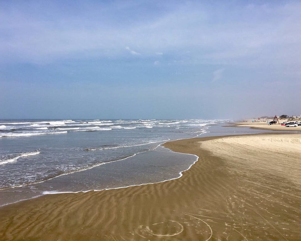 Orla de Xangri-Lá RS em dia ensolarado, com faixa de areia e mar calmo