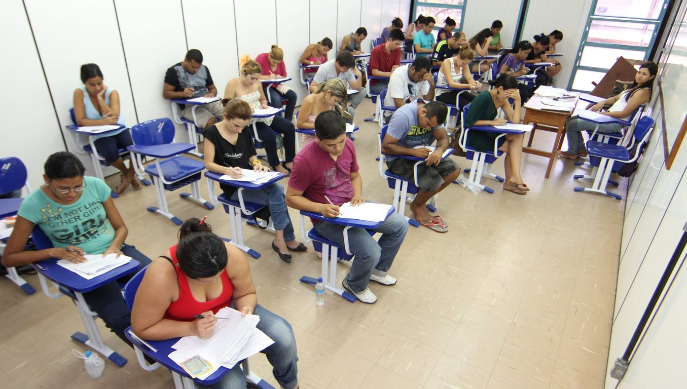 Estudantes em sala realizando prova escrita em universidade pública