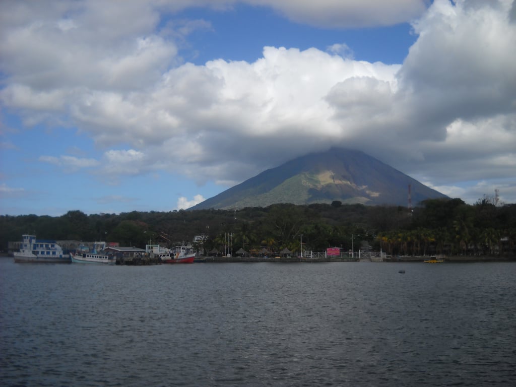 Rio largo entre morros verdes, com pequenas embarcações ao entardecer