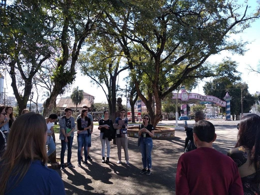 Foto do exterior de um campus do IFFar com estudantes em atividade, árvores e pórtico de entrada.