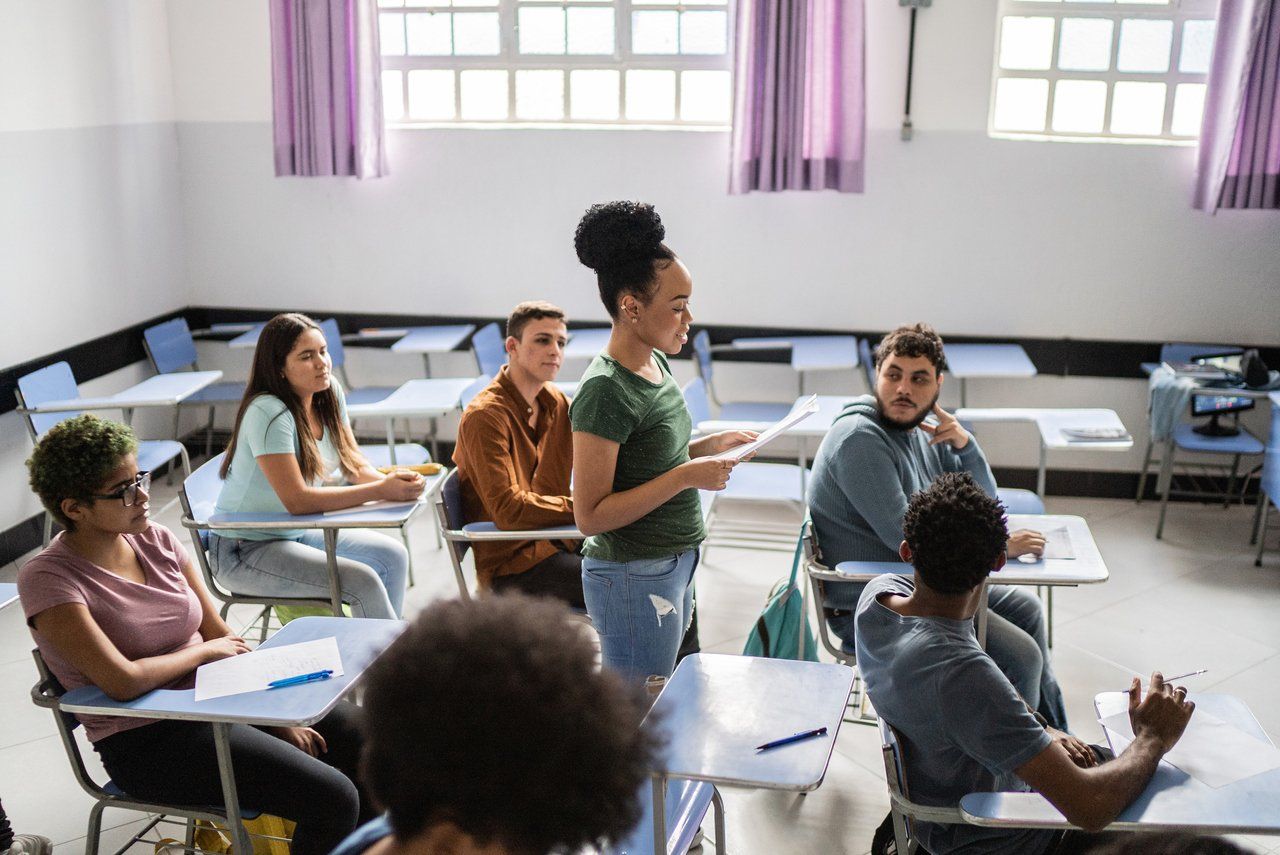 Sala de aula universitária com docentes e estudantes adultos em atividade