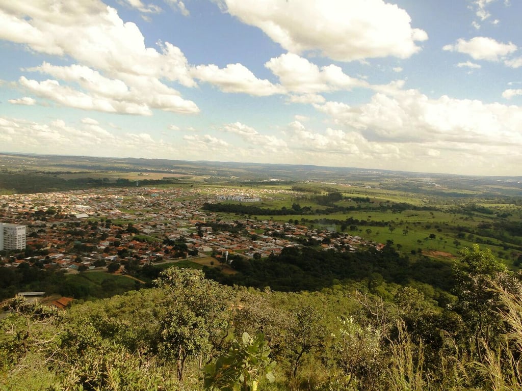 Vista aérea de Senador Canedo GO, com bairros residenciais, áreas verdes e a paisagem urbana em dia ensolarado.