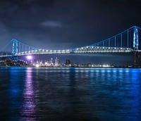Ponte Hercílio Luz iluminada à noite, com o skyline de Florianópolis ao fundo