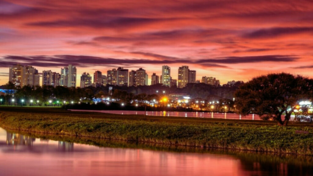 Skyline de Curitiba refletido na água do Parque Barigui, ao entardecer