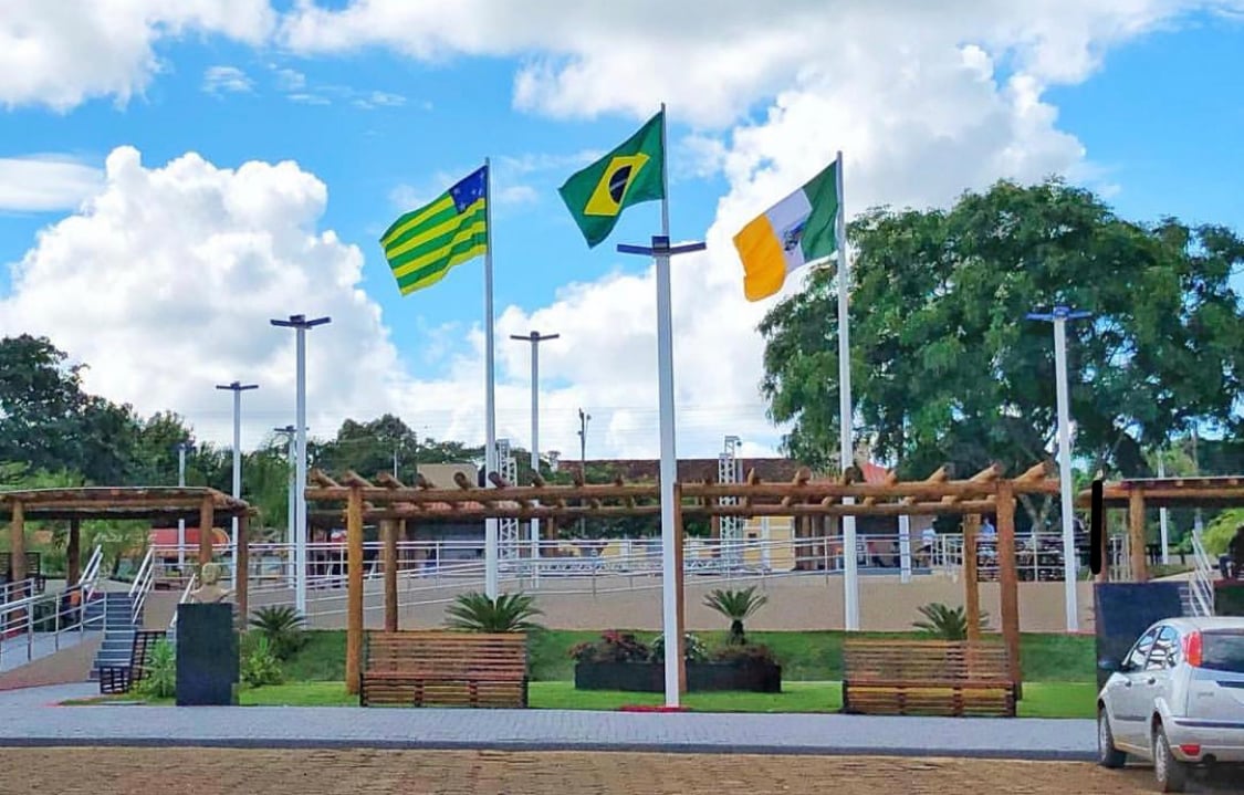 Bandeiras de Vianópolis em espaço urbano, com paisagismo e área pública ao fundo