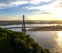 Vista aérea de Ilhéus ao entardecer, mostrando ponte e mar na Bahia.