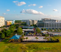 Vista do campus universitário da FURG com prédios modernos, área verde e estudantes caminhando ao ar livre.