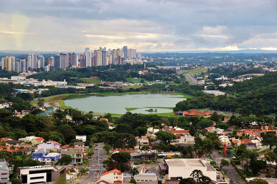 Vista aérea do centro de Curitiba com áreas verdes ao fundo