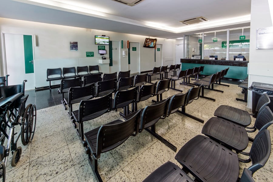 Sala de espera de ambulatório, com cadeiras e recepção ao fundo