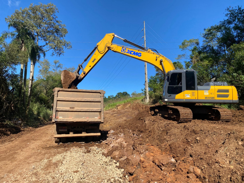 Operador de retroescavadeira realizando manutenção de via urbana no RS, em enquadramento horizontal