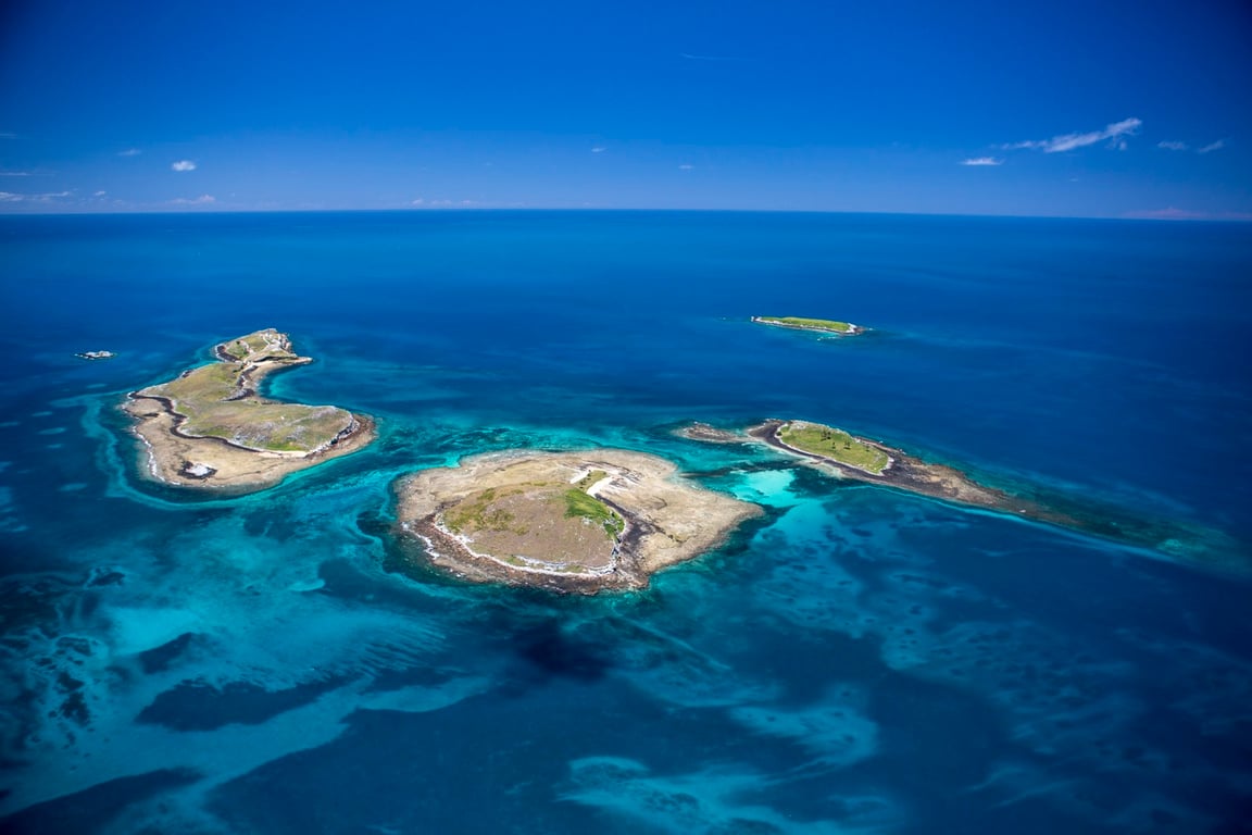 Vista aérea do Parque Nacional Marinho dos Abrolhos, com ilhas e recifes de coral em águas turquesa