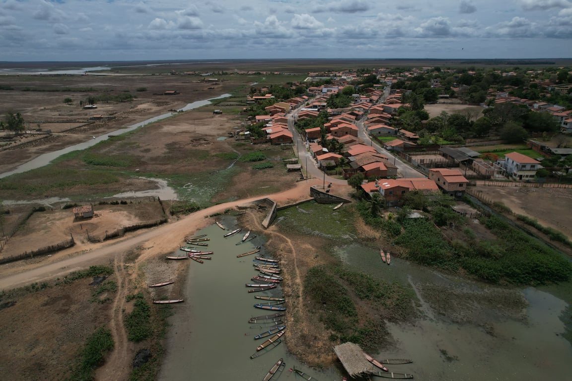 Vista aérea horizontal da Baixada Maranhense, com rio, casas e estrada rural