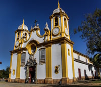 Vista urbana de Bom Jesus do Amparo MG com igreja matriz e morros ao fundo.