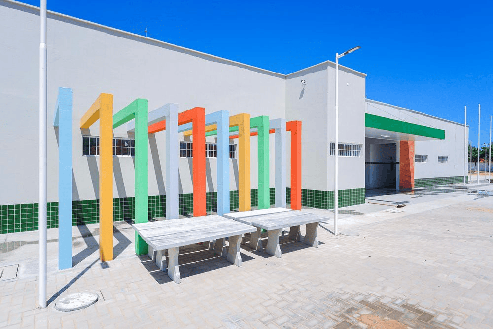 Fachada de escola pública no Piauí, com área externa colorida e mesas