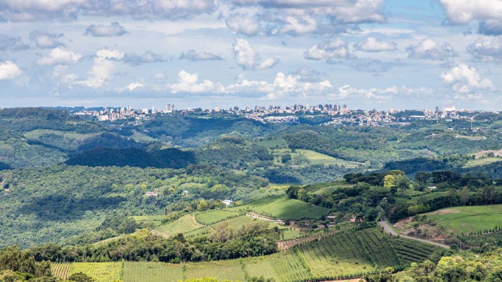Paisagem do interior do Rio Grande do Sul, com colinas verdes e cidade ao fundo